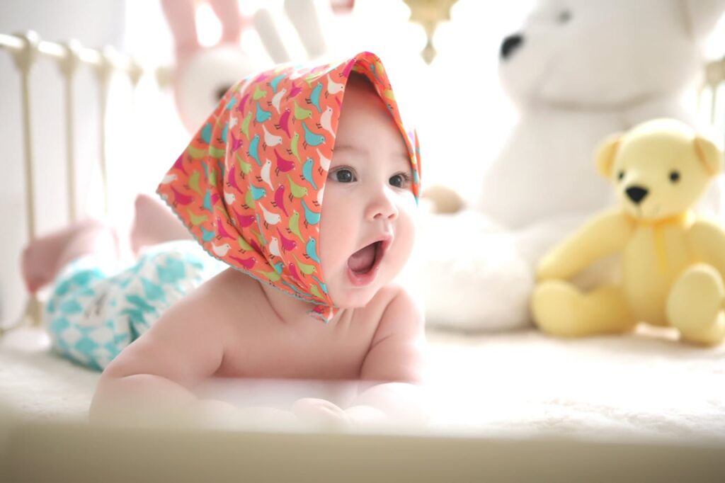 pexels-photo-265987 Charming baby with colorful scarf surrounded by cute plush toys, highlighting innocence indoors.